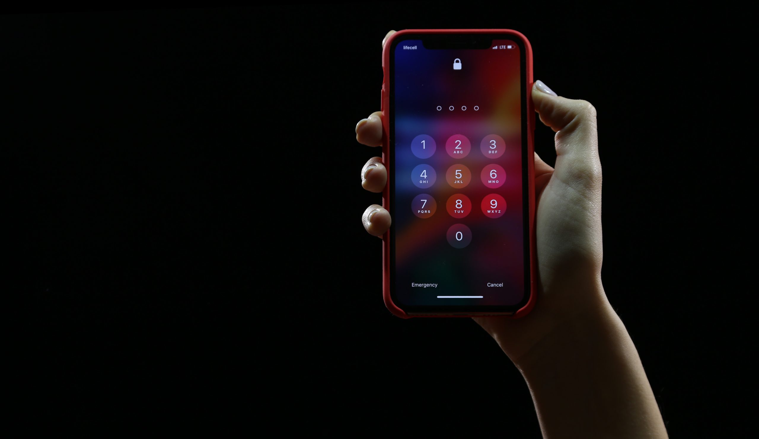 A hand holding a smartphone over a black background.