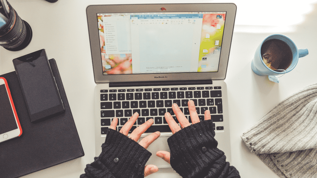 Overhead shot of woman typing on laptop with tea