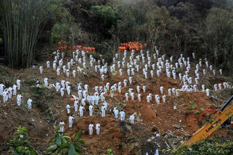 This photo taken on March 27, 2022 shows rescuers standing in a silent tribute for victims at the site of the China Eastern Airlines plane crash in Tengxian county, Wuzhou city, in China's southern Guangxi region