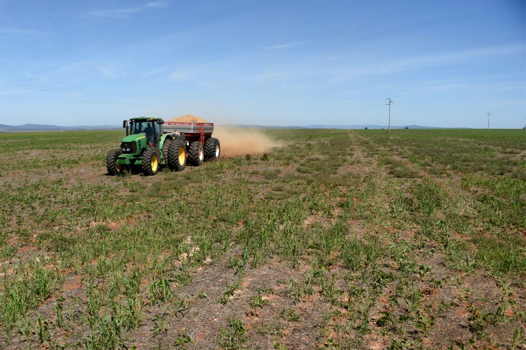 A tractor sprays stone dust in a field next to a pile of stone dust at the Vargem Dourada farm in Padre Bernardo, Goias State, Brazil on May 19, 2022