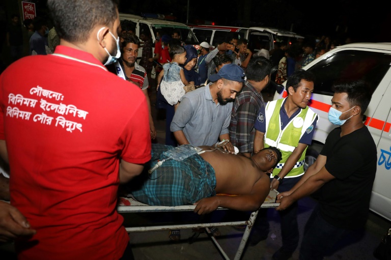 Rescue workers and civilians carry an injured victim to a hospital in Chittagong, Bangladesh, after a massive fire broke out at a local container storage center