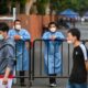 Workers wearing protective gear stand behind a fence blocking a street in a residential area under a Covid-19 lockdown in the Huangpu district of Shanghai