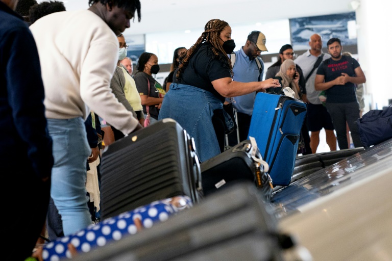 Travelers pick up their baggage while arriving at Ronald Reagan Washington National Airport in Arlington, Virginia, on July 2, 2022
