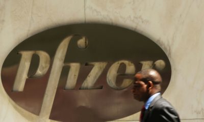 A man walks past the Pfizer logo on the drug maker's headquarters in New York