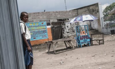 A child stands next to a road stall selling cellular telephone cards and internet access in Kinshasa in 2015