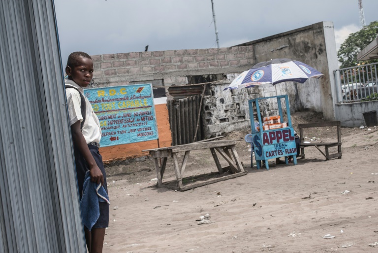 A child stands next to a road stall selling cellular telephone cards and internet access in Kinshasa in 2015