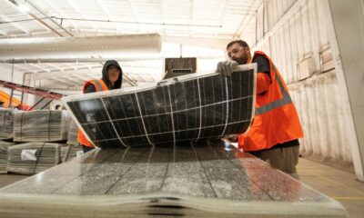 Workers push damaged solar panels into a machine to be recycled at the We Recycle Solar plant in Yuma, Arizona