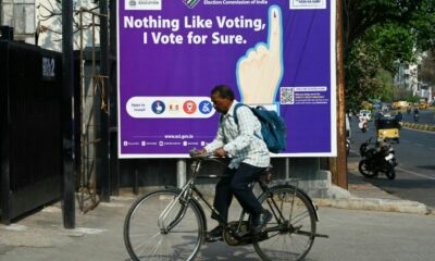 A man rides past an election awareness poster displayed on a street ahead of India’s upcoming general elections, in Hyderabad